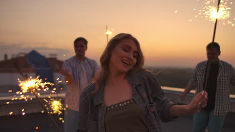 Girl-on-the-roof-moves-her-arms-and-body-beautifully-a-dance-with-her-friends-on-a-summer-evening-with-big-bengal-light.-It's-a-pleasure-sunset-before-night.-Their-hair-blows-beautifully-in-the-wind.